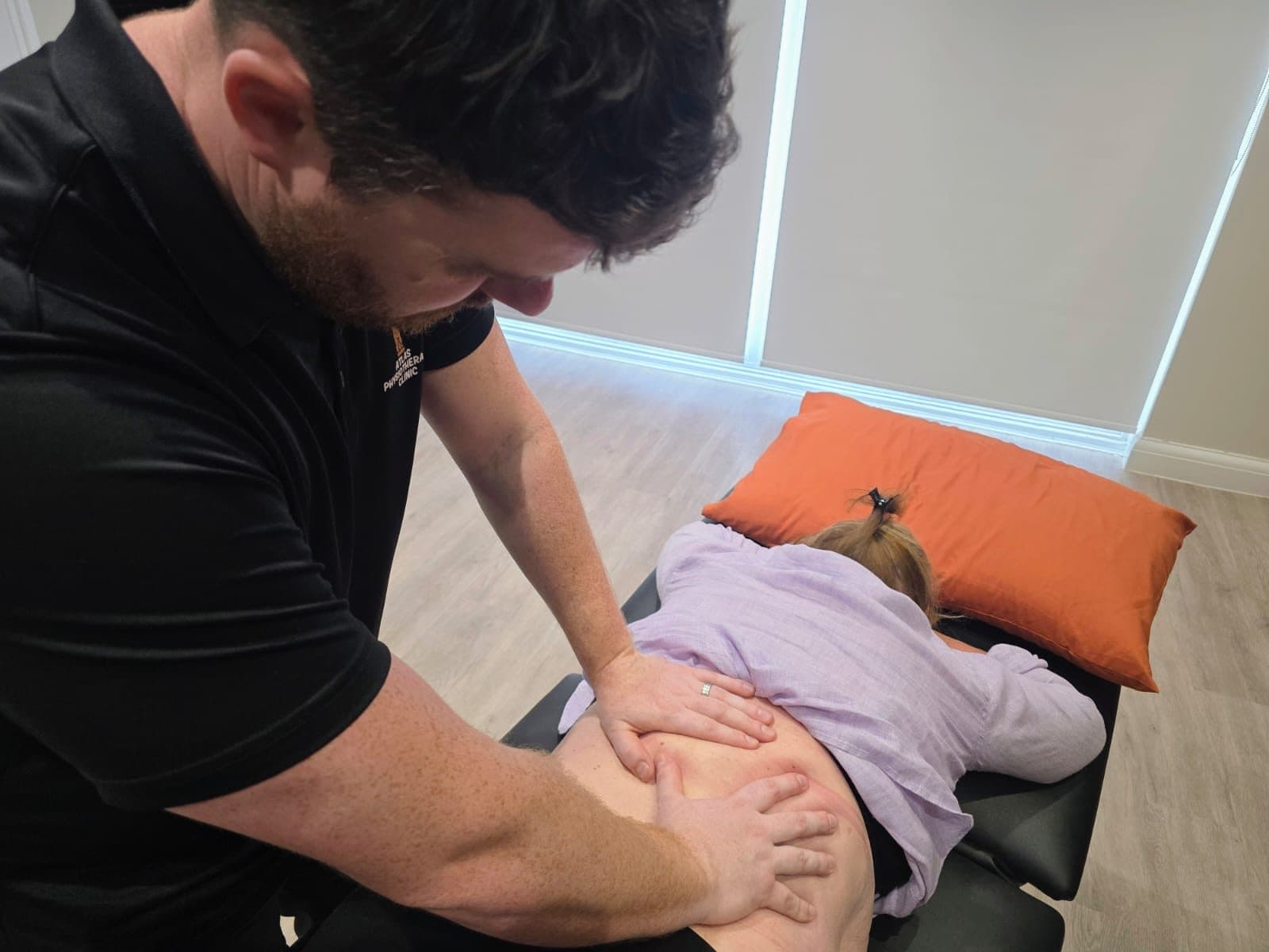 Connor delivering deep tissue work on a patient's upper back during a sports massage session
